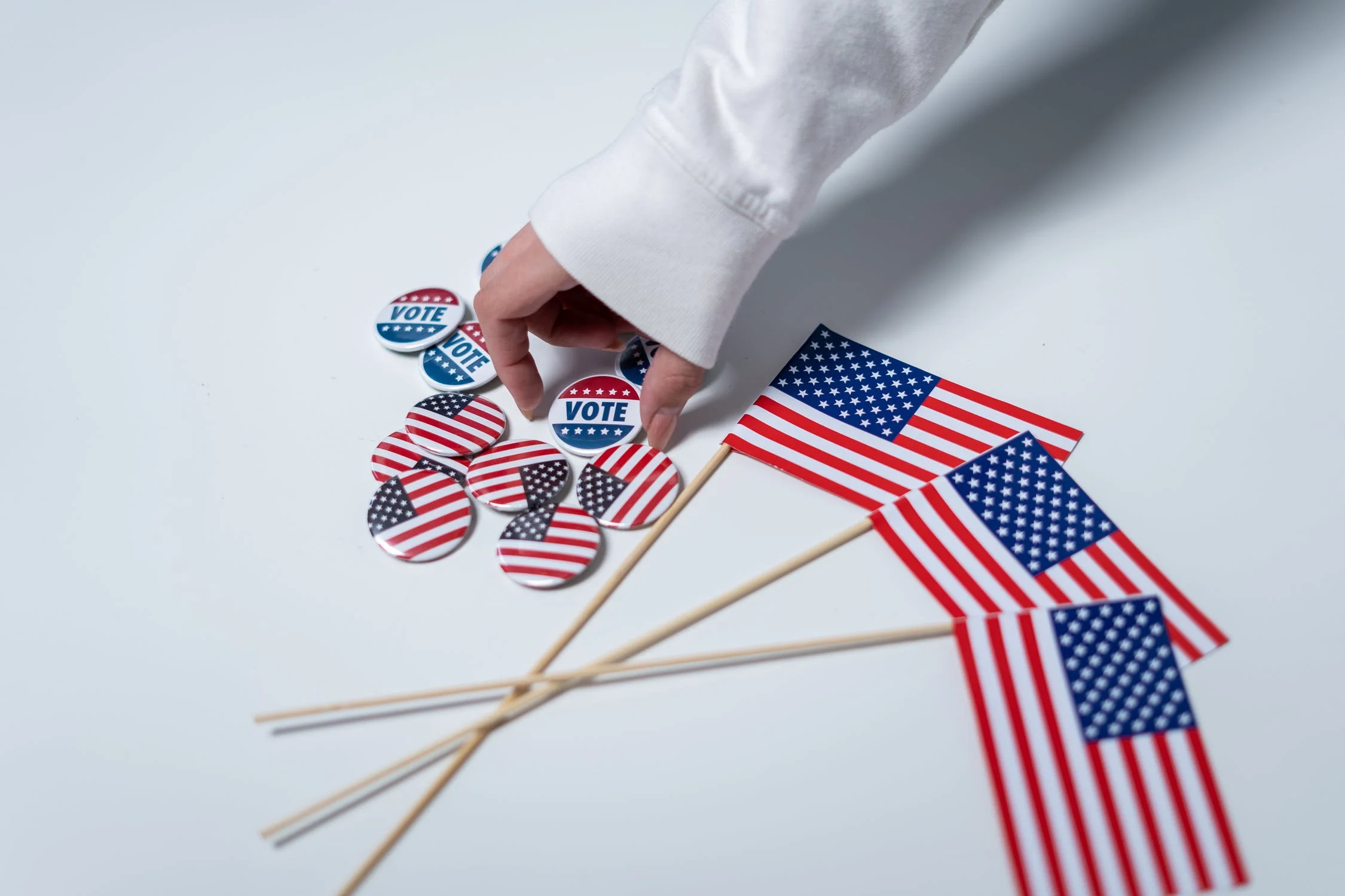 Hand picking up vote button next to small American flags on table