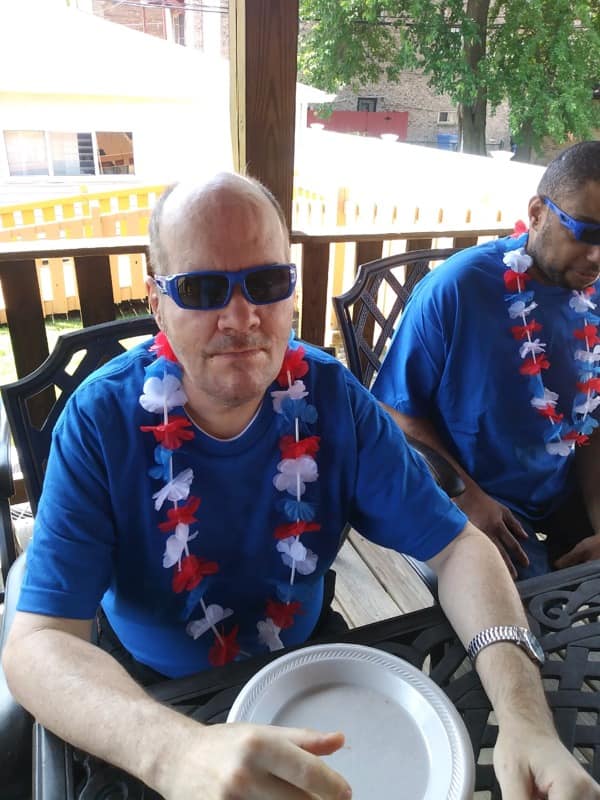 Screen Shot from 7-10-2020 Friday update video man in a blue shirt with a red, white and blue lei