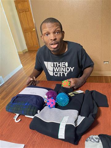 Man sits by sweatshirts and toys he received as Christmas presents