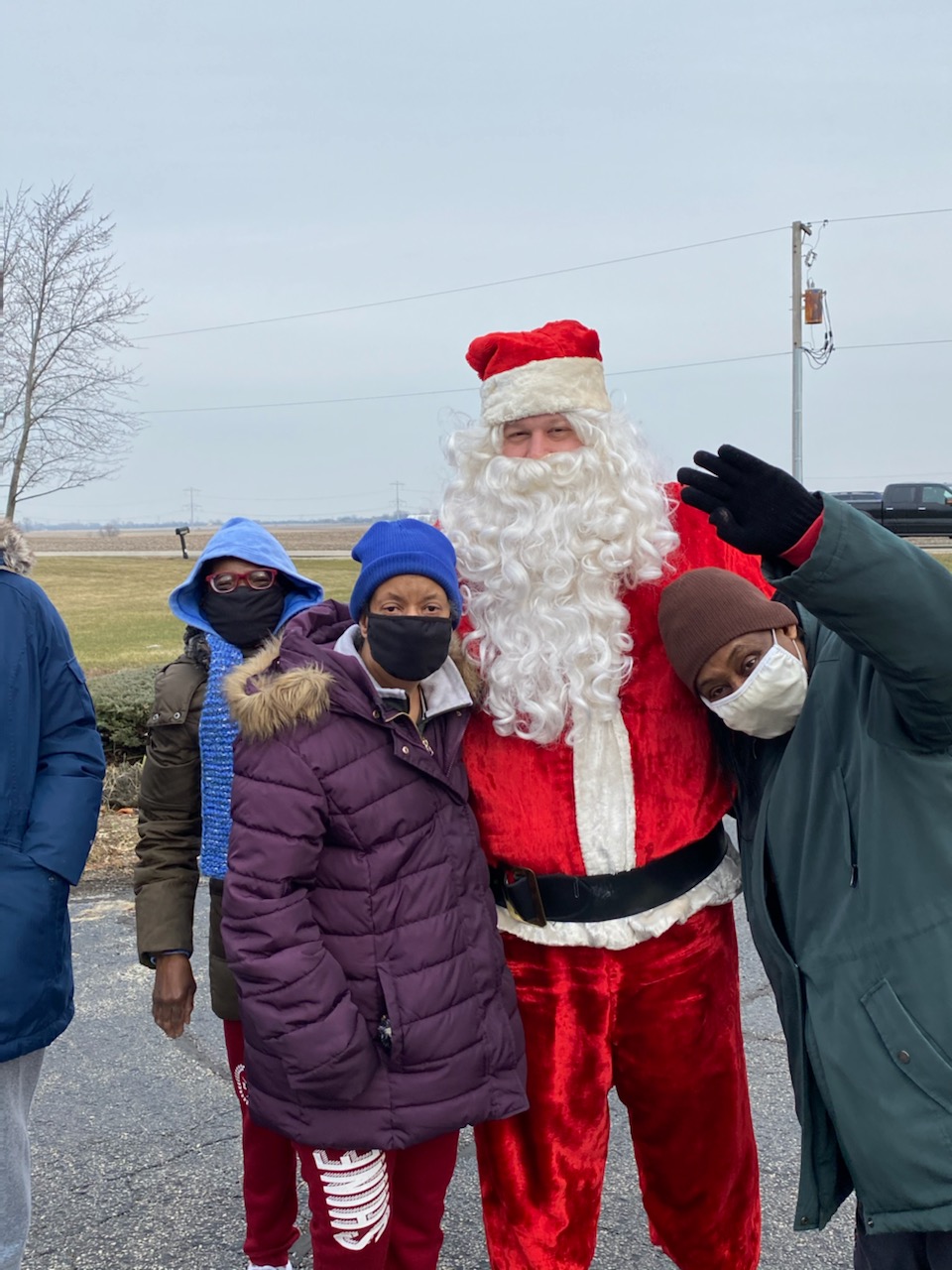 Three women stand beside a man dressed as Santa